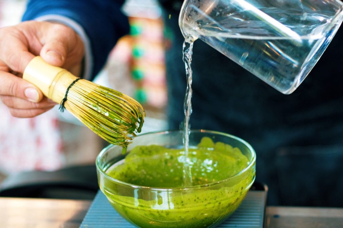 Matcha green tea being whisked in a bowl