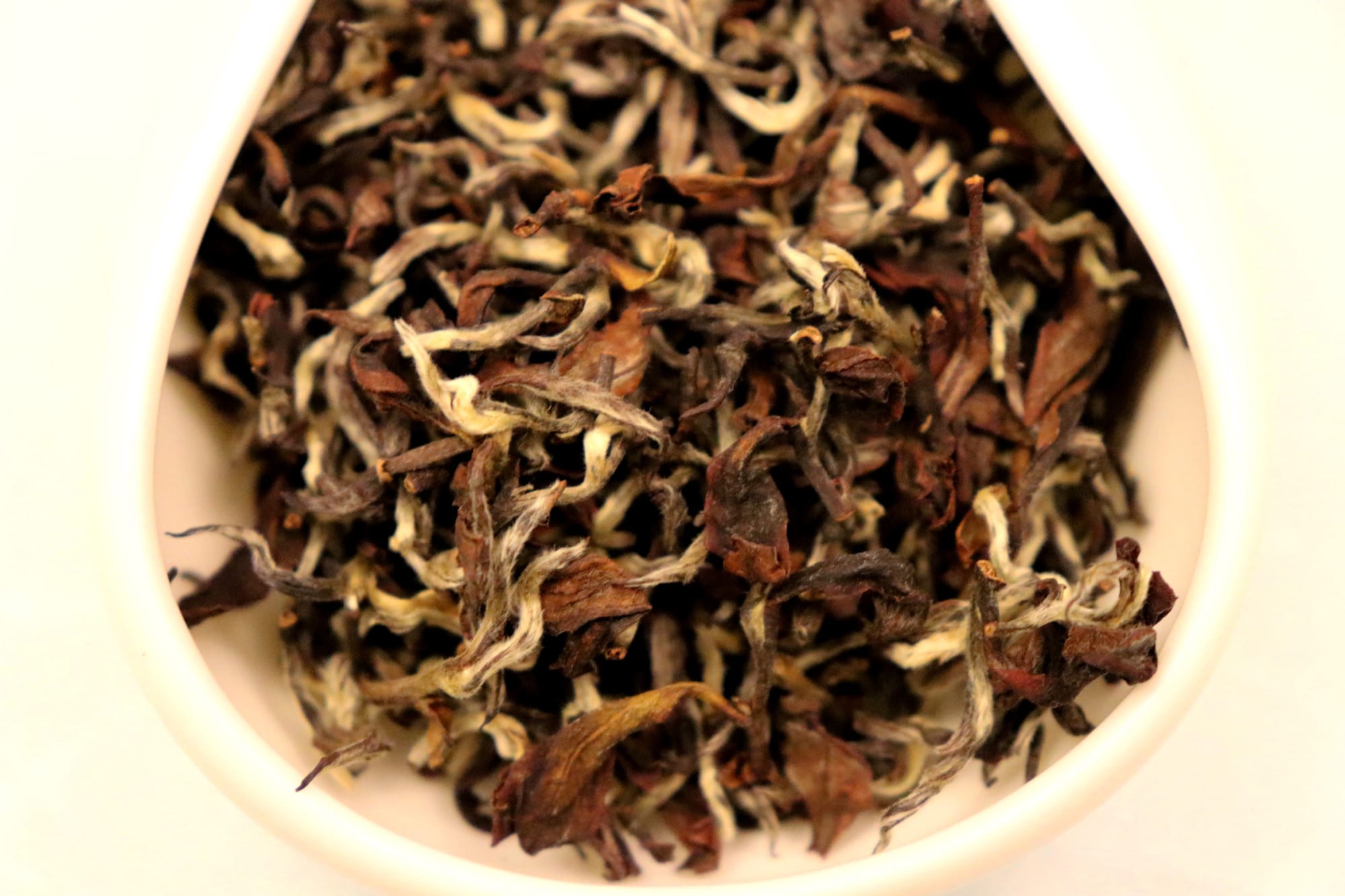 Dong Fang Mei Ren tea leaves in a white bowl