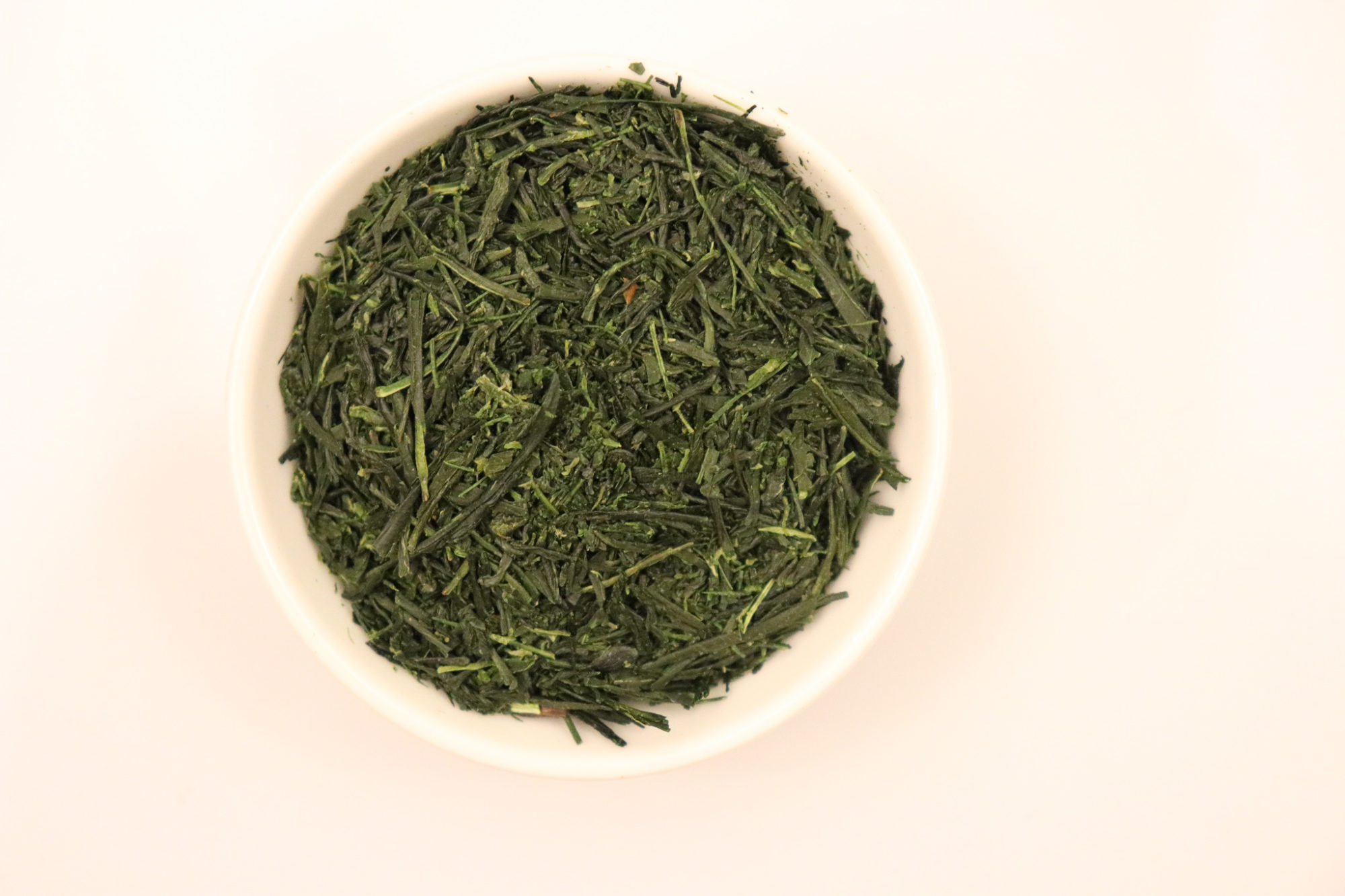 The Green Tea Shop Kabusecha - Gokou closeup of dark green leaves in a white dish on a off white background