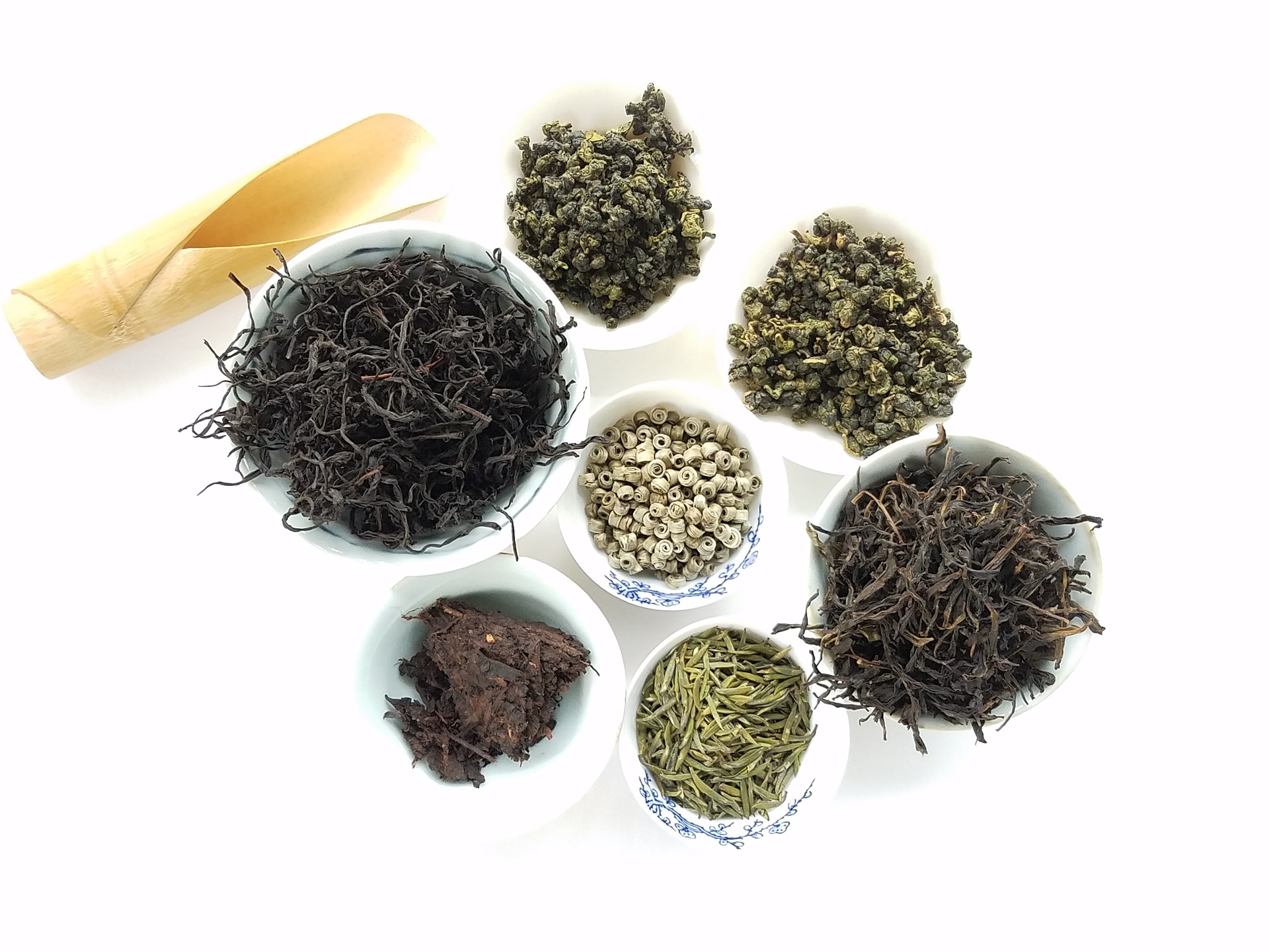 How to Get Started Drinking Tea - A variety of teas displayed in white bowls with a bamboo scoop
