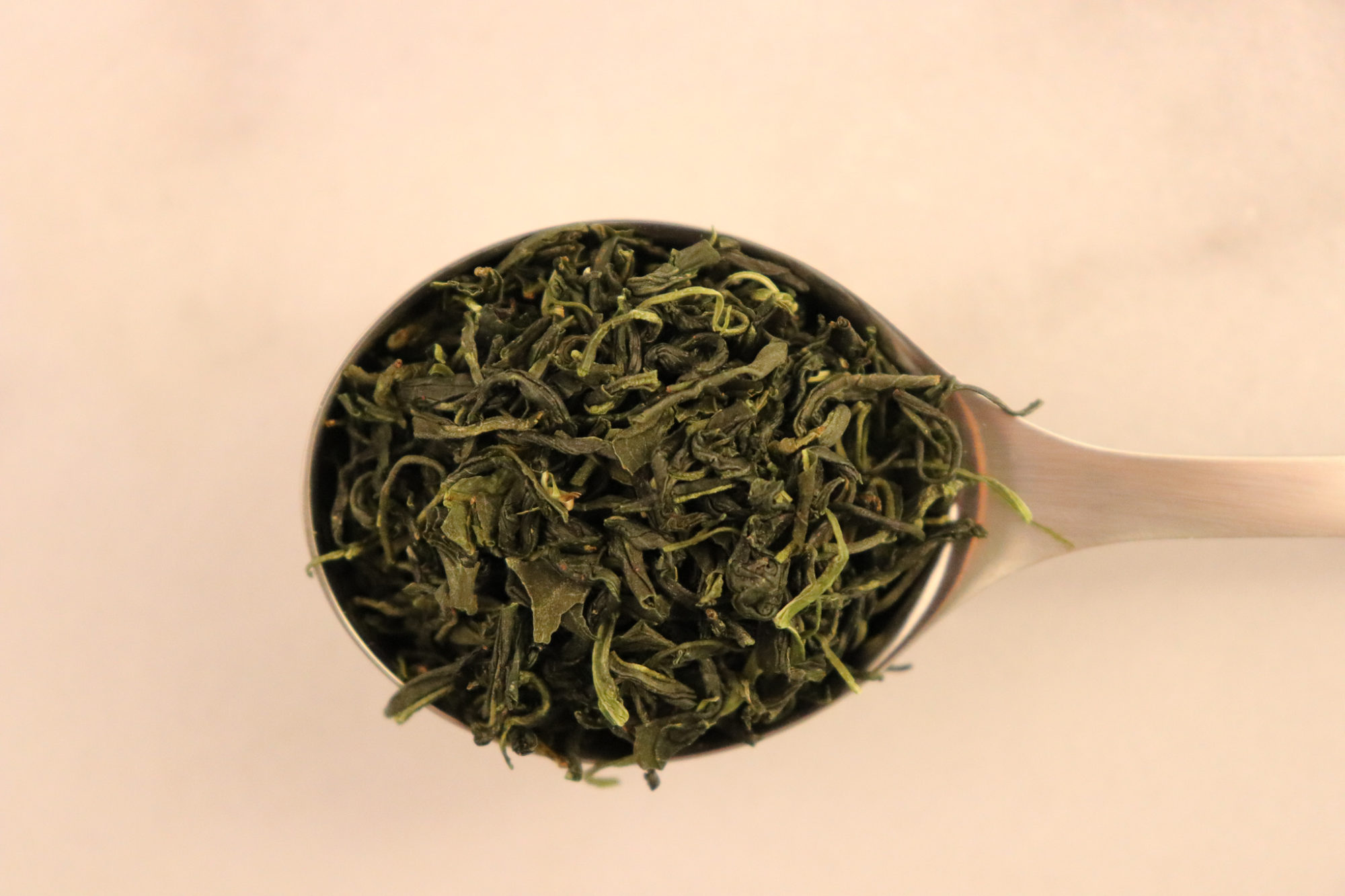 DAVIDsTEA Organic Korean Sejak - green tea leaves in a silver spoon on a white background