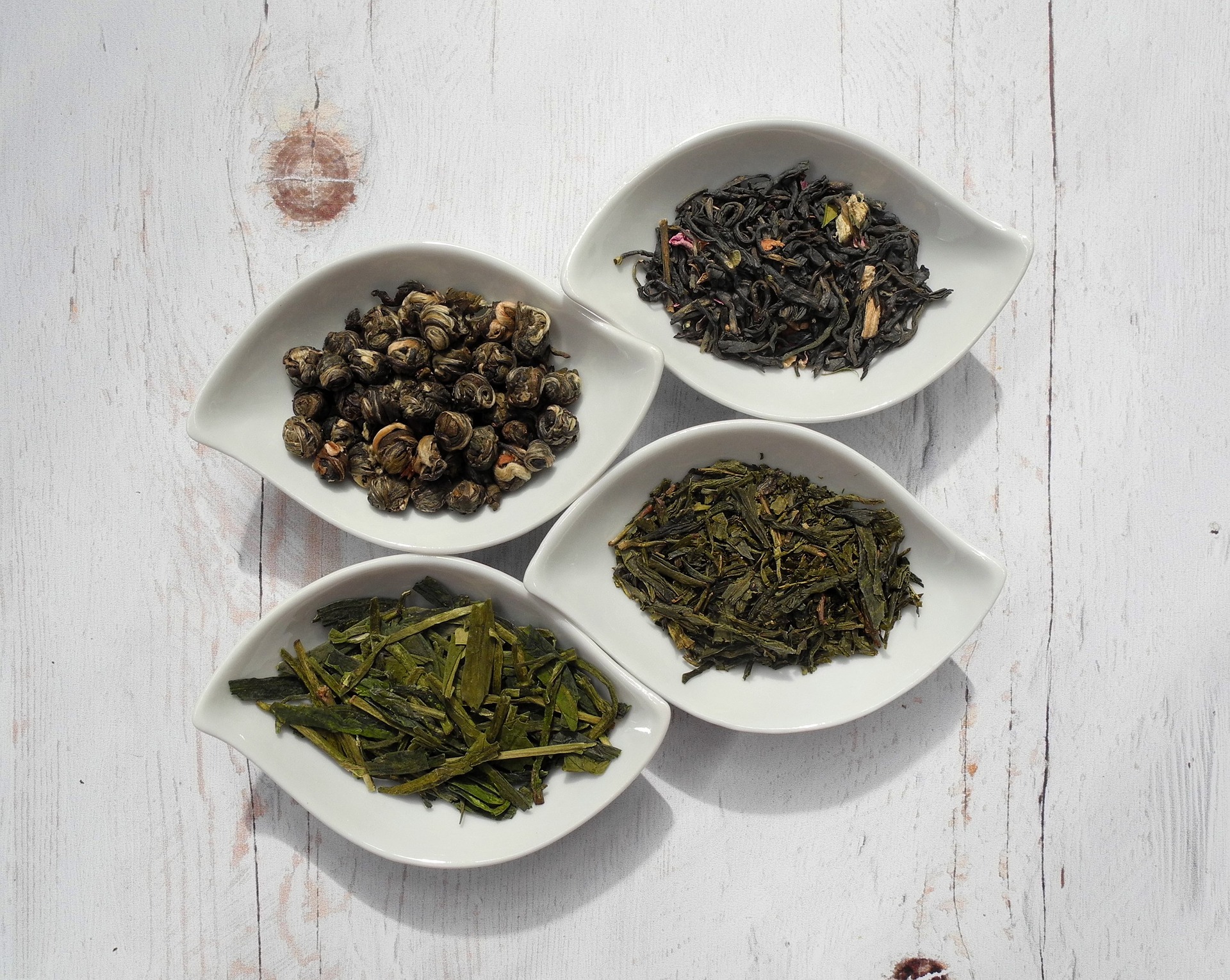 Get Started Drinking Tea - a variety of green teas displayed in white leaf-shaped bowls against a whitewashed wood background