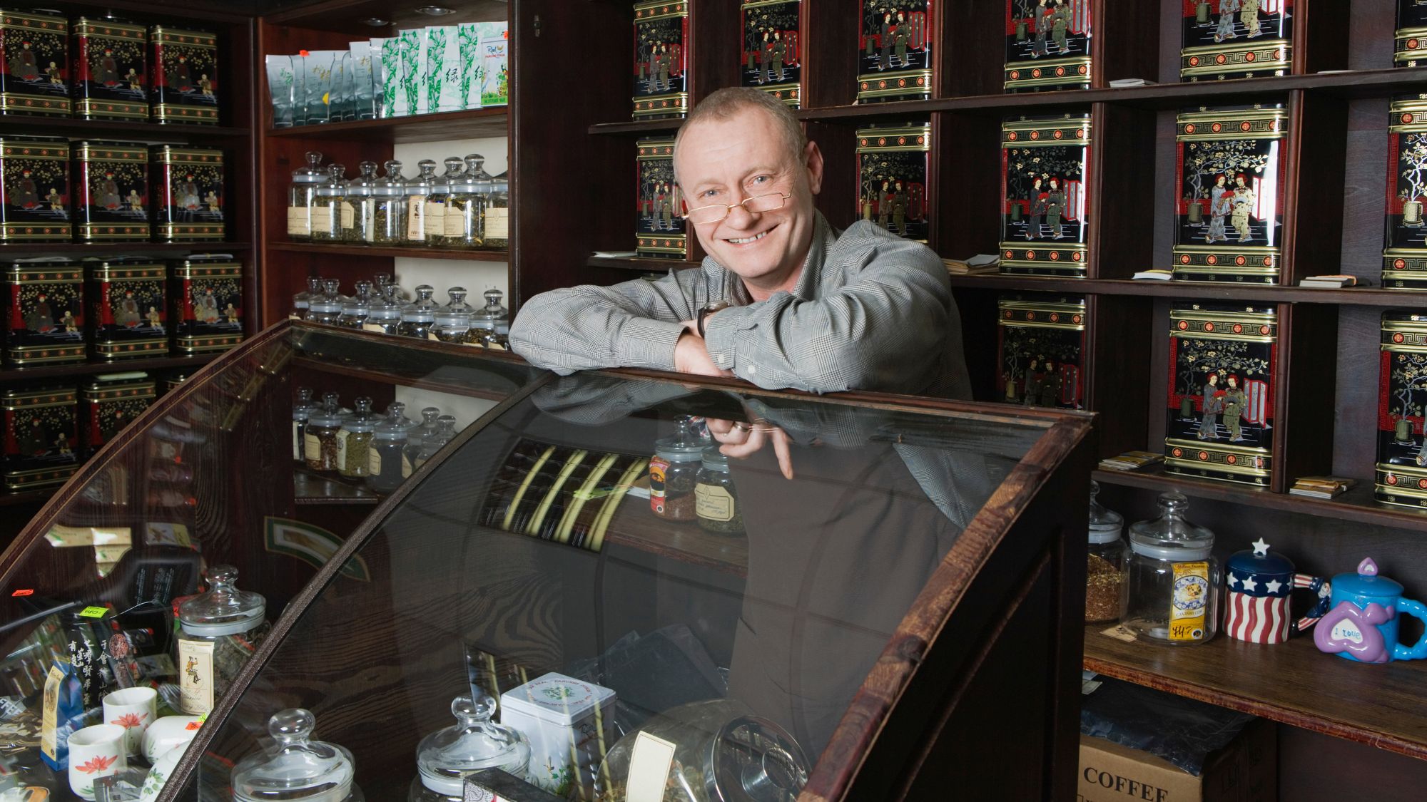 A man smiling behind the counter at a tea shop - 8 Things You Should Do Before Starting a Tea Business