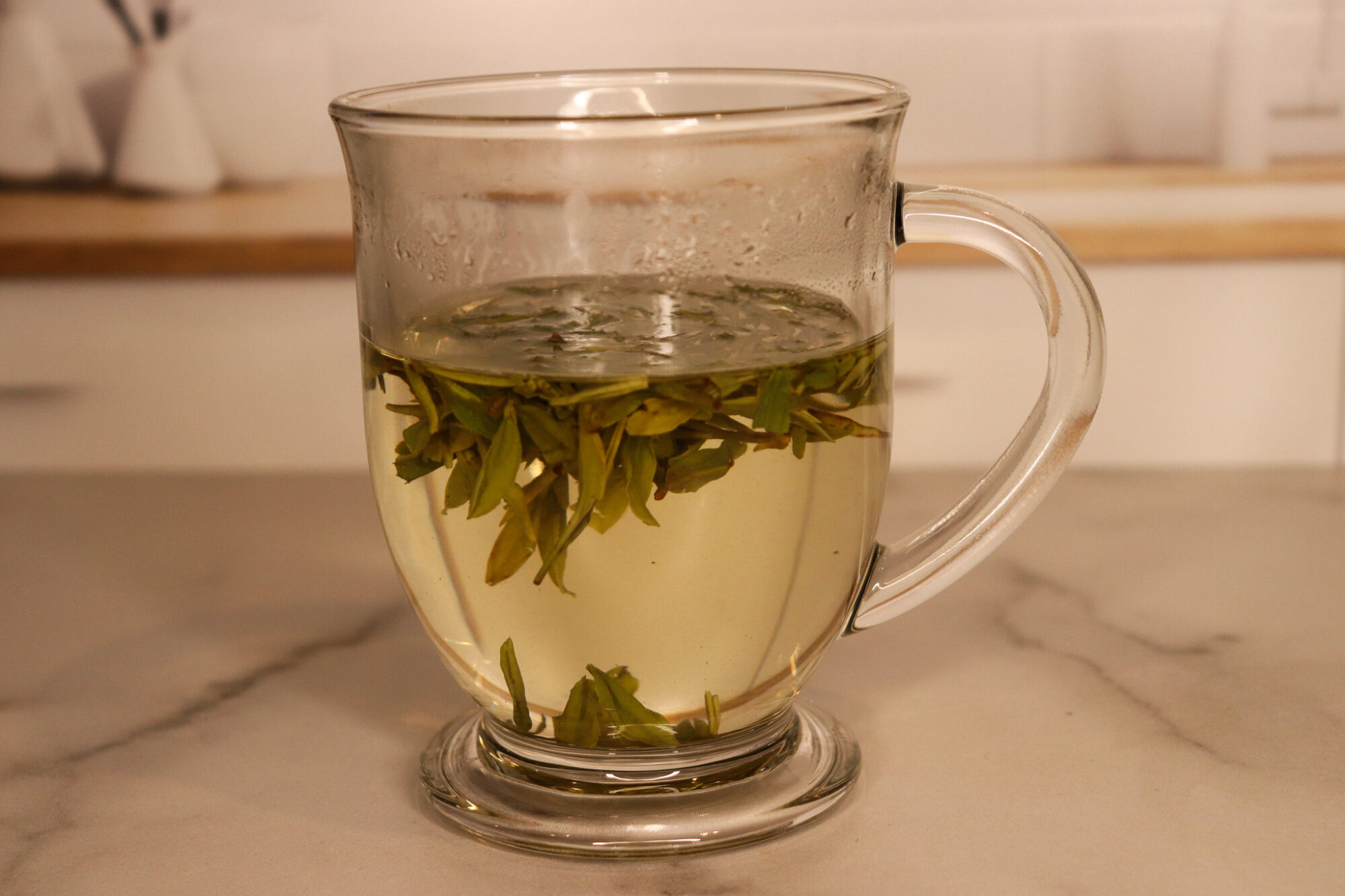 Grandpa Style Tea - Dragonwell leaves floating in a clear mug
