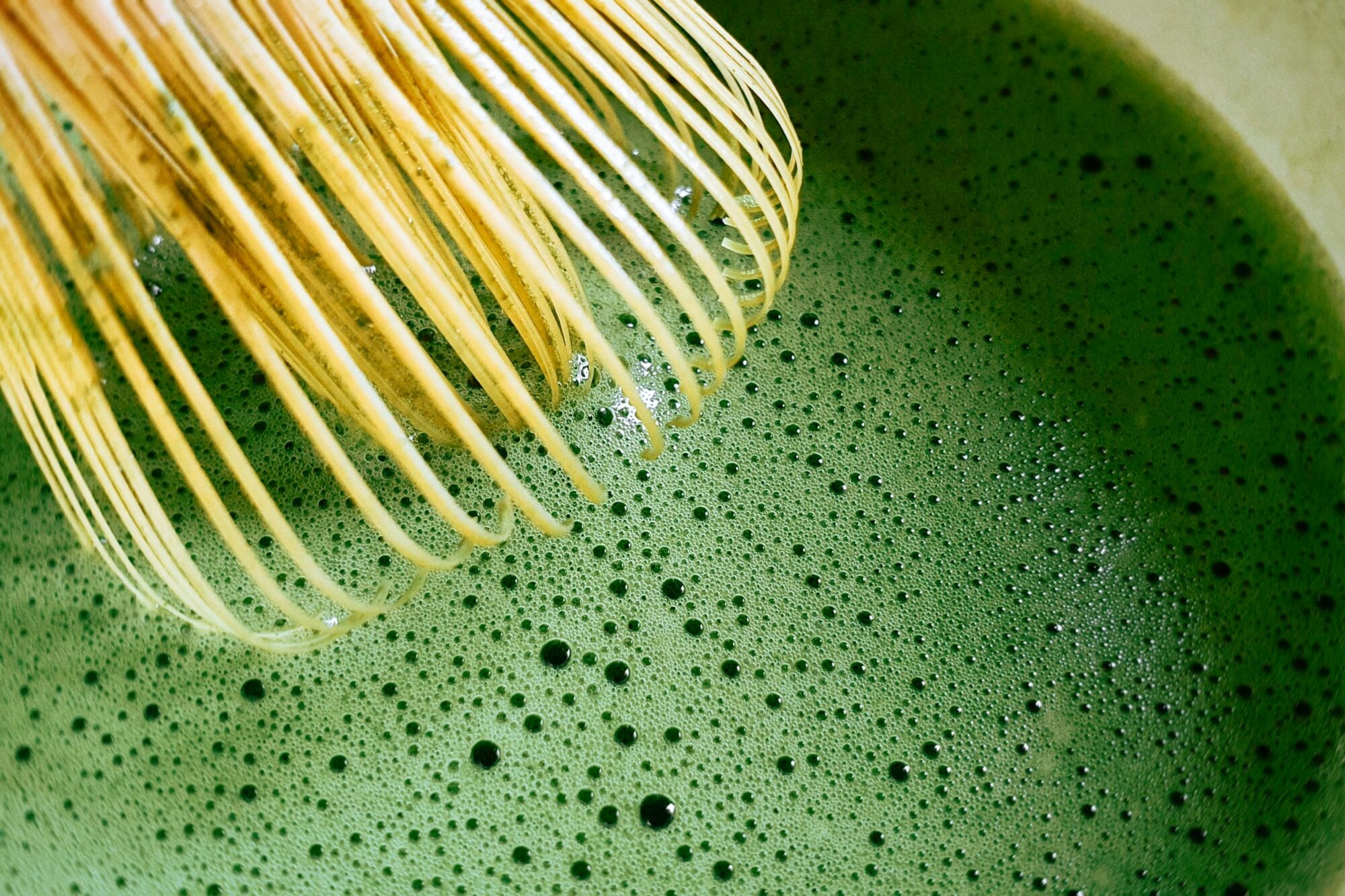 Does Matcha Cause Hair Loss? - a bamboo chasen over a bubbly bowl of matcha green tea