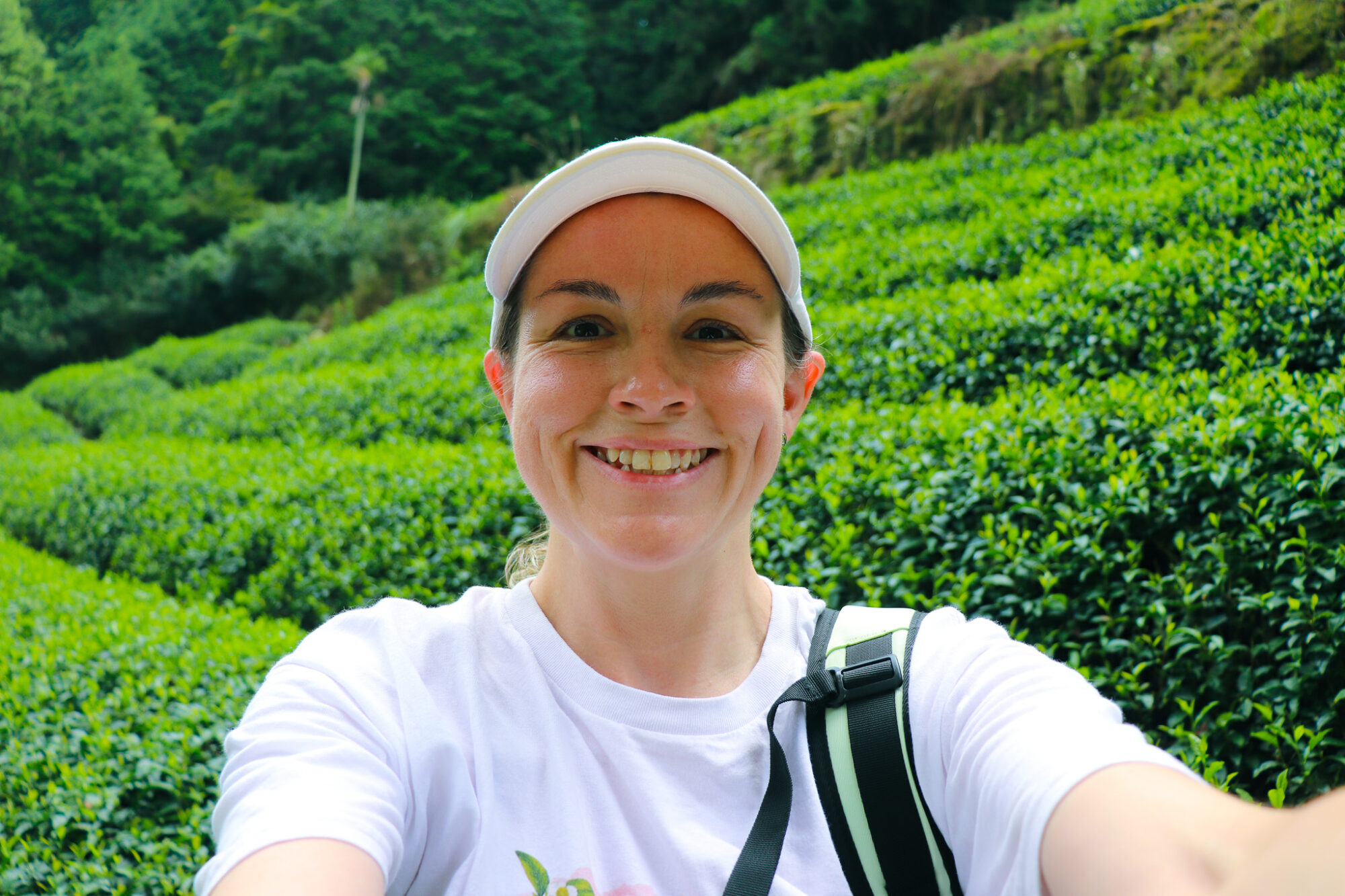 A very happy Nicole standing in a tea field at Obubu Tea Farms
